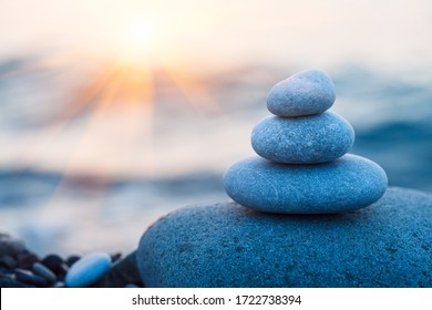 zen pebble stones on sea beach at morning sunrise, meditation, harmony and balance concept, copy space