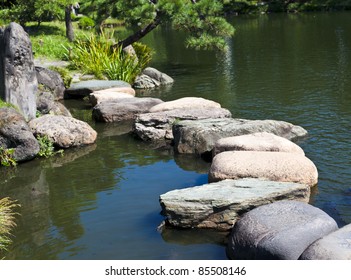 Zen Stone Path In A Japanese Garden Across A Tranquil Pond With Carps And Turtles