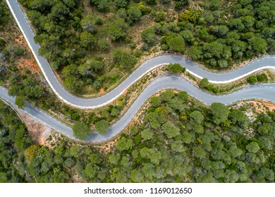 Zenit view from a drone of a picturesque and lonely road, zigzagging, surrounded by trees and nature - Shutterstock ID 1169012650