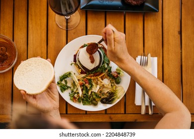 Zenithal Shot Of A Woman Pouring Hot Sauce On A Burger