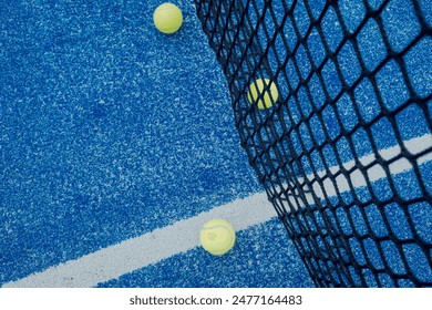 zenithal view of three balls at the base of the net of a paddle tennis court. - Powered by Shutterstock