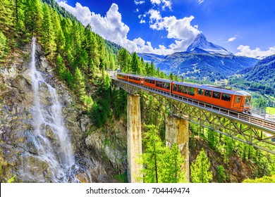 Zermatt, Switzerland. Gornergrat tourist train with waterfall, bridge and Matterhorn. Valais region. - Shutterstock ID 704449474