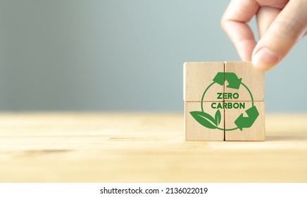 Zero Carbon And Net Zero Emissions Concept. Carbon Neutral. Climate Neutral Long Term Strategy. Sustainable Business Development. Hand Puts Wooden Cube With Green Zero Carbon Icons On Grey Background.