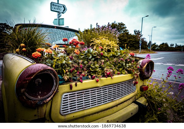 Zero emissions car with the bonnet plenty of\
colorful flowers. Road sign in the background pointing to Bangor,\
Gwynedd, North Wales