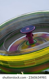 zero gravity ride at local fair or carnival at night long time exposure creating spinning motion and movement yellow neon lights spinning amusement park vertical image room for type spinning top 