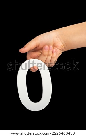 Zero in hand. The number zero is clasped in a hand isolated on a black background. Number zero white in a child's hand on a black background.