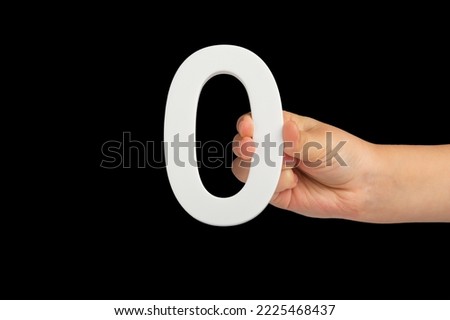 Zero in hand. The number zero is clasped in a hand isolated on a black background. Number zero white in a child's hand on a black background.