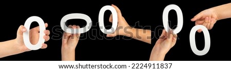 Zero in hand.Big set. The number zero is clasped in a hand isolated on a black background. Number zero white in a child's hand on a black background.