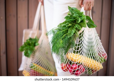Zero waste concept with copy space. Woman holding cotton shopper and reusable mesh shopping bags with vegetables, products. Eco friendly mesh shopper. Zero waste, plastic free concept