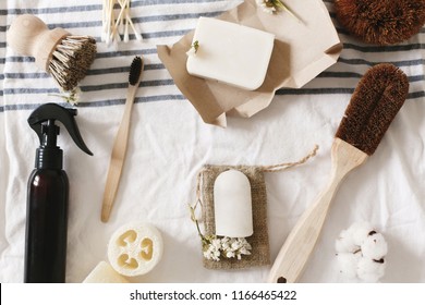 zero waste concept, flat lay of plastic free items. natural luffa, bamboo toothbrush, brush, coconut soap, handmade detergent and crystal deodorant on towel, eco bathroom essentials