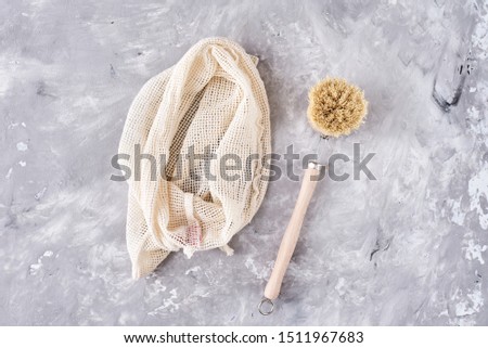 Zero waste concept. Multi-use bag and wooden brush on gray background.