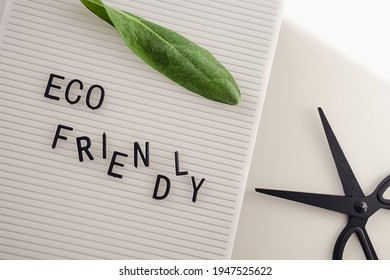 Zero Waste Concept, Pros And Cons. Black Letters On A Peg Board With Message Text Eco Friendly, Scissors And A Fresh Green Leaf On White Background. Flat Lay.