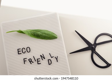 Zero Waste Concept, Pros And Cons. Black Letters On A Peg Board With Message Text Eco Friendly, Scissors And A Fresh Green Leaf On White Background. Flat Lay.