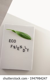 Zero Waste Concept, Pros And Cons. Black Letters On A Peg Board With Message Text Eco Friendly And A Fresh Green Leaf On White Background. Flat Lay.