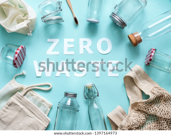 Zero\
waste concept. Textile eco bags, glass jars and bamboo toothbrush\
on blue background with Zero Waste white paper text in center. Eco\
friendly and reuse concept. Top view or flat\
lay