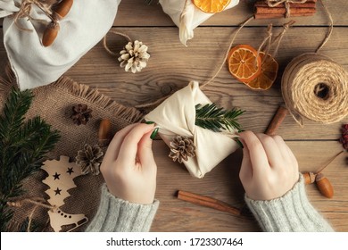 Zero waste and eco friendly christmas concept. Female hands wrap gifts in natural fabric with ornaments made of natural materials, top view, flat lay - Powered by Shutterstock