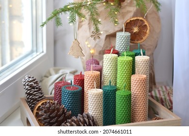 zero waste, eco friendly xmas. happy new year. multicolored candles on a wooden tray, natural christmas tree in a craft bag,  candle made of natural wax with texture of honeycomb bees. 