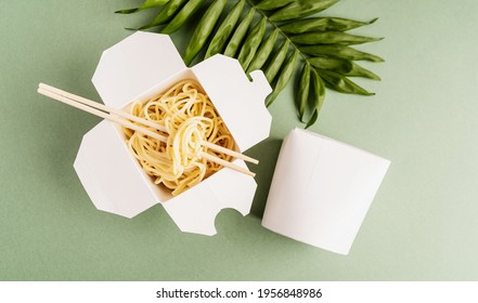 Zero waste and ecology concept. Opened WOK paper box with noodles and chopsticks, mock up design top view flat lay on green background