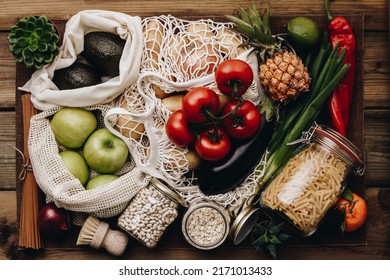 Zero waste food shopping. Fruit and vegetables in cotton bags, pasta, cereals and legumes in glass jars, herbs and spices on wooden background. Healthy food, clean eating, eco friendly, no plastic con