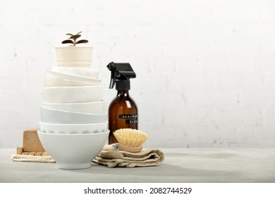 Zero waste home kitchen cleaning concept, front view of dishes, dish washing brush, organic soap bar, kitchen towel, house plant and eco safe all purpose cleaner in reused glass jar - Powered by Shutterstock