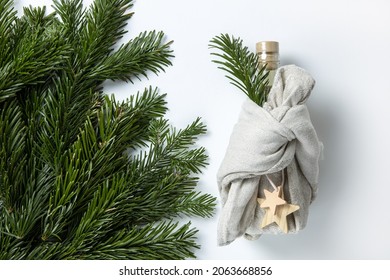 Zero Waste Merry Christmas Winter Gift Wrapping, Bottle In Japanese Furoshiki Style In Linen Fabric, Decorated With Natural Green Branches Of Fir Nobilis. Concept Eco-friendly Creative Package.