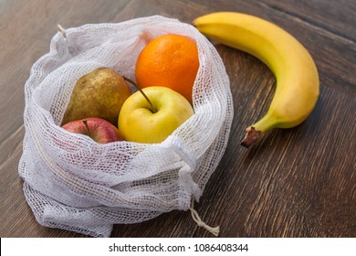 Zero Waste, Plastic Free Recycled Textile Produce Bag For Carrying Fruit (apple, Orange, Pear And A Banana) Or Vegetables, A Wooden Surface. Bags Are Made With A Sewing Machine Out Of Old Curtains.