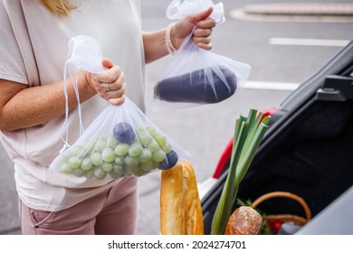 Zero Waste And Plastic Free Shopping. Woman Loading Groceries In Reusable Mesh Bags Into Car Trunk