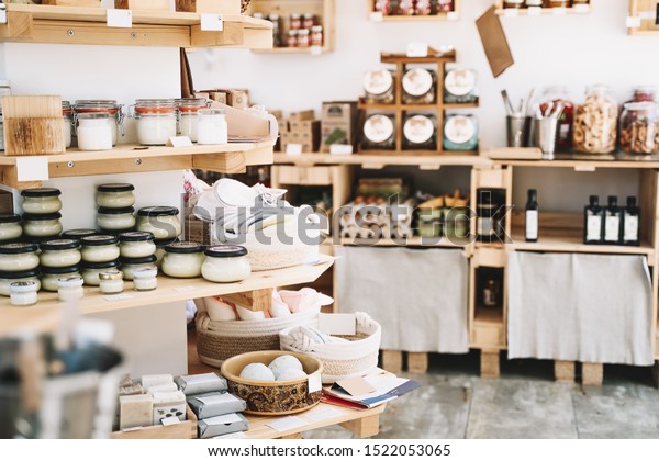 Zero waste shop interior details. Wooden\
shelves with different food goods and personal hygiene or cosmetics\
products in plastic free grocery store. Eco-friendly shopping at\
local small businesses