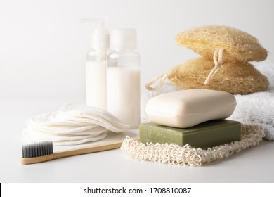 Zero waste, sustainable bathroom and lifestyle. Bamboo toothbrush, natural soap bar, loofah sponge, cotton pads, homemade DIY beauty products in reusable bottles over white background.