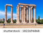 Zeus temple in summer, Athens, Greece. It is famous landmark of Athens. Tourists look at majestic Ancient Greek ruins. Great columns of classical building in Athens city center. Travel concept.