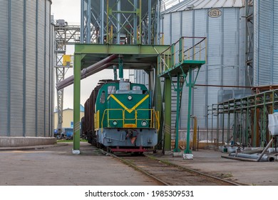 Zhmerynka, Ukraine - Autumn 2018: Small industrial electric locomotive TGM23 delivers hopper cars for loading grain.  Large new Elevator.