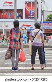 ZHUHAI-CHINA-SEPTEMBER 5, 2013. Young And Old Chinese Women Waiting On A Zebra Crossing. Life Expectancy At Birth; Female In China Was Last Measured At 76.67 In 2013, According To The World Bank.