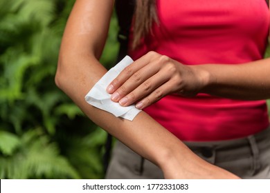 Zika and West Nile viruse mosquito woman using repellent wipes wiping arm with wet wipe applying bug spray chemical product.