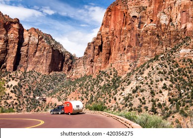 Zion National Park, Utah. Red vintage trailer going down the road. Majestic mountain scenery. 