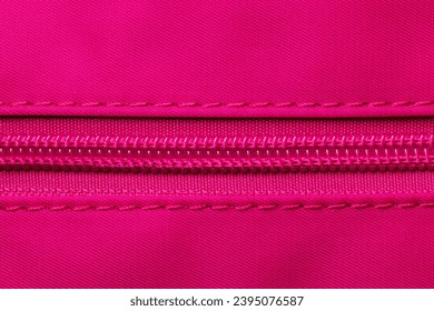 Zip fastener background texture. A high-resolution close-up of a detail from a closed plastic zip fastening on a backpack made of an elastic pink nylon fabric. Macro photo.