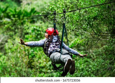 zipline zip line canopy wire forest jungle woman safety back adult tourist wearing casual clothing on zipline trip selective focus against blurred forest zipline zip line canopy wire forest jungle wom