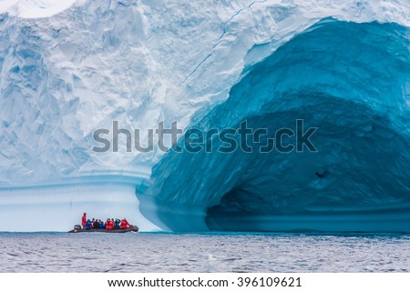 Zodiac in front of enormous ice berg in Antarctica