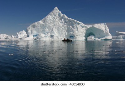 Zodiac With People In Front Of An Iceberg At Antarctica