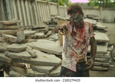 Zombie attacks. Angry bloody zombie man stretches its arms forward towards the victim standing in destroyed city. Halloween. Horror movie. Zombie apocalypse.