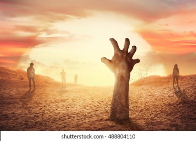 Zombie hand rising from the grave at sunset