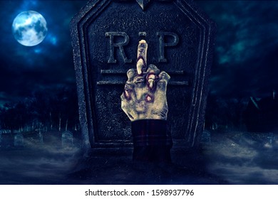 Zombie Hand Showing Middle Finger In Front Of Tombstone, Creepy Cemetary In The Background.