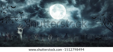 Zombie Rising and hands Out Of A Graveyard cemetery scary In Spooky dark Night full moon. Holiday event halloween concept.