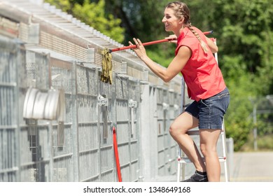 Zookeeper Woman Working On Cleaning Cage In Animal Shelter With Sweep 