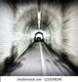 Zoom Blur Image Of An Old Dark Pedestrian Tunnel With Unidentifiable People Emerging Into The Light