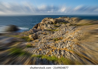 A Zoom Blur Photo Of A Scenic, Unique, Ancient Volcanic Rock Coast Under A Blue Sky With Ocean Clouds.