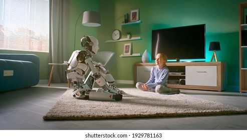 Zoom in view of girl sitting on carpet near TV set and talking with android while resting at home in weekend
