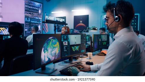 Zoom In View Of Mature Man With Headset Using Computer While Launching Spacecraft With Astronaut Remotely With Team In Flight Control Center