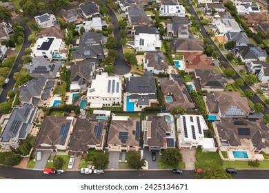Zoomed out aerial view of an upmarket neighbourhood with modern prestige homes on a cul-de-sac with rooftop solar and pools in outer suburban Sydney, Australia.