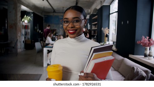 Zoom-in portrait of happy successful young beautiful African business woman smiling at camera working at modern office.