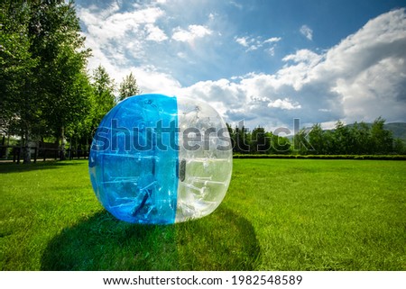 Zorbing Balloon on the summer lawn. inflatable zorb ball outdoor. Leisure activity concept with copy space.